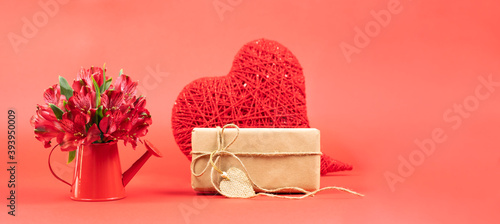 Greeting card. Red alstroemerias in a watering can and gifts on a red background