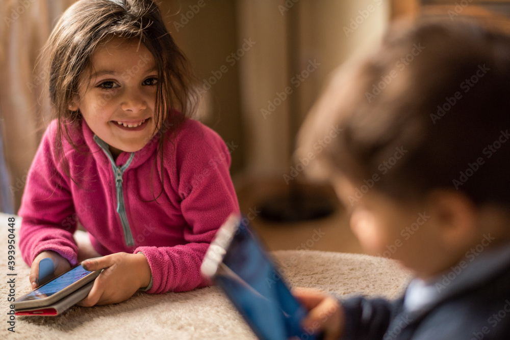 Little brothers at home with smartphones playing. Girl smiling. Little brothers at home with smartphones playing. Girl smiling.