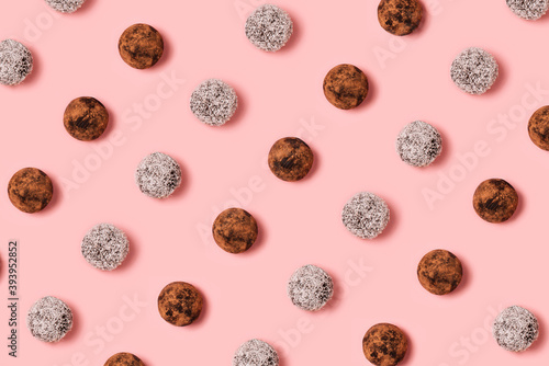 Healthy natural candies homemade from natural ingredients, handmade energy ball with dried fruits. Vegan sweets on pastel pink background. Top view. Flat lay. Food concept.