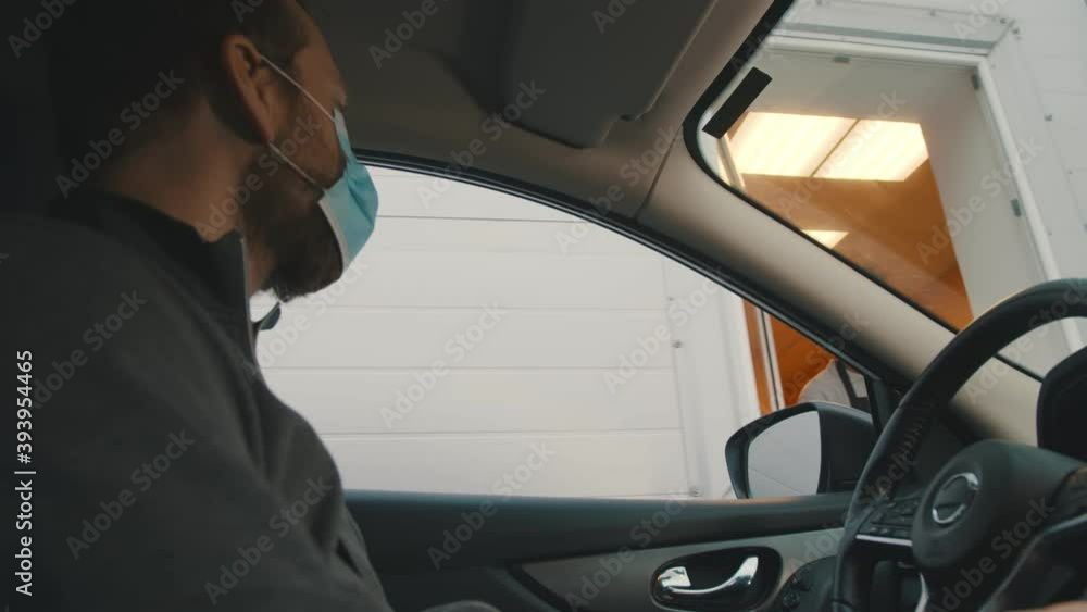 Man driver in mask paying with smartphone app in drive through window Man driver in mask paying with smartphone app in drive through window