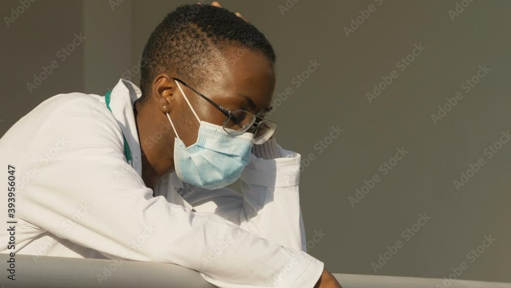 coronavirus pandemic - black thoughtful doctor relaxes in a moment of pause coronavirus pandemic - black thoughtful doctor relaxes in a moment of pause