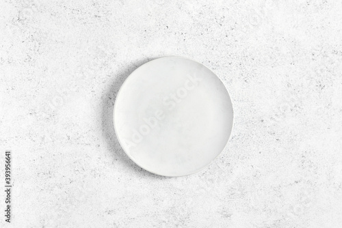 Empty white plate over light stone background