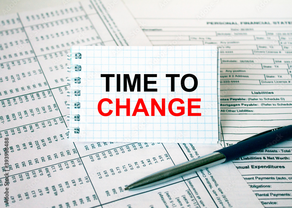 Notepad with text Time To Change lying on financial tables with a pen Notepad with text Time To Change lying on financial tables with a pen