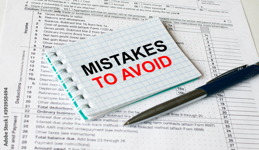Fototapeta premium Notepad with text Mistakes To Avoid lying on financial tables with a pen