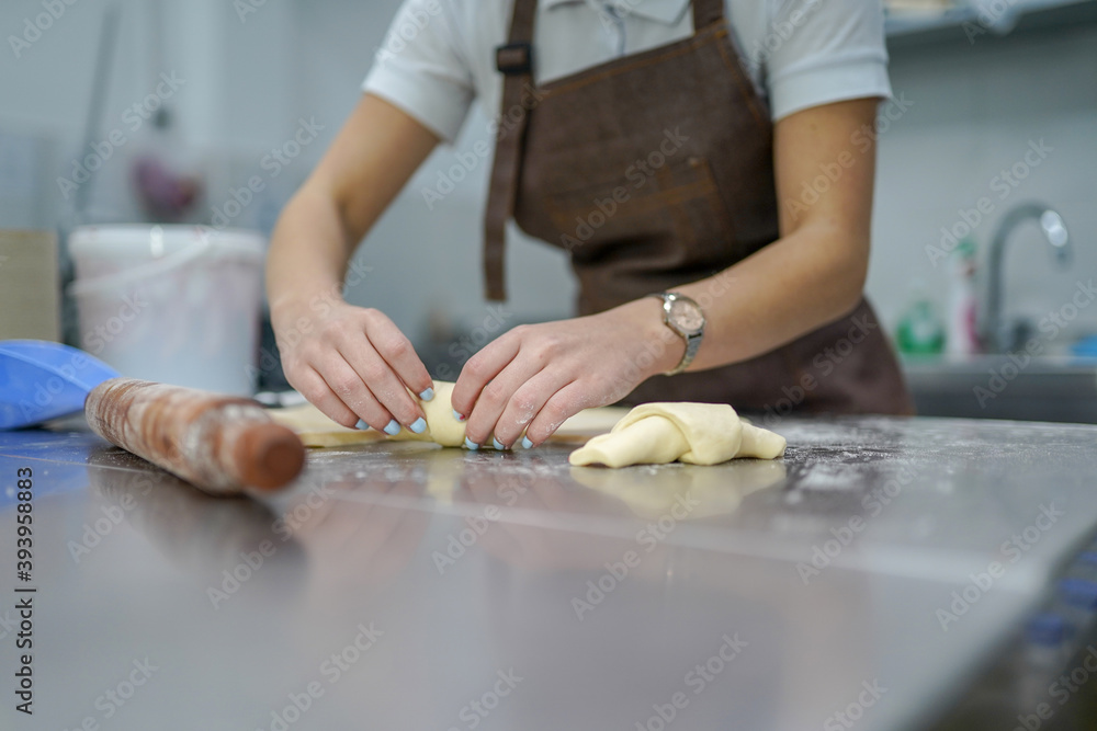 Young woman making croissants in bakery