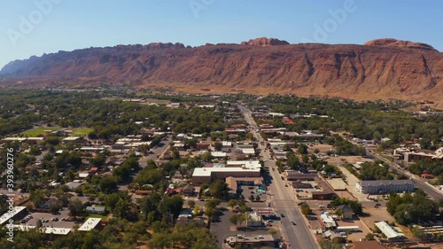 drone shot of moab utah with red mountains behind the city