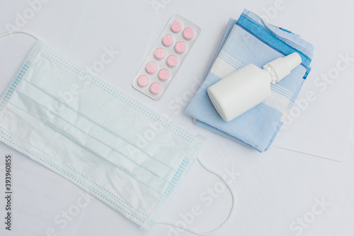 Nasal spray bottle, medical mask, pills and handkerchief, close up, white background, copy space photo