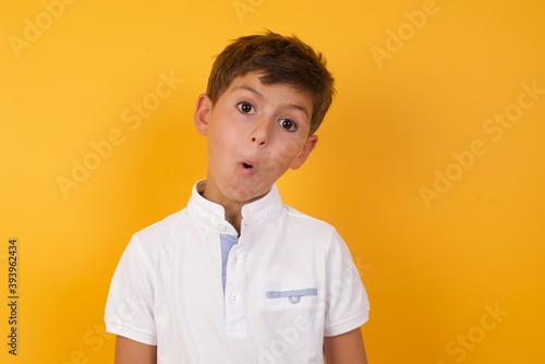 little cute boy kid wearing white t-shirt against yellow wall expressing disgust, unwillingness, disregard having tensive look frowning face, looking indignant with something.