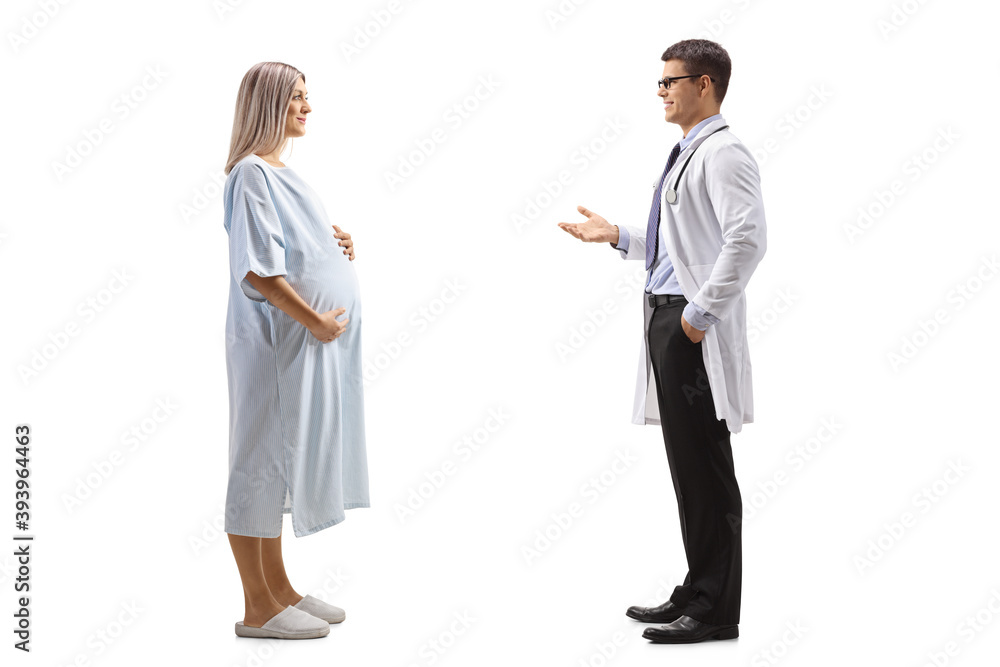 Full length profile shot of a male doctor talking to a pregnant woman patient in a hospital gown