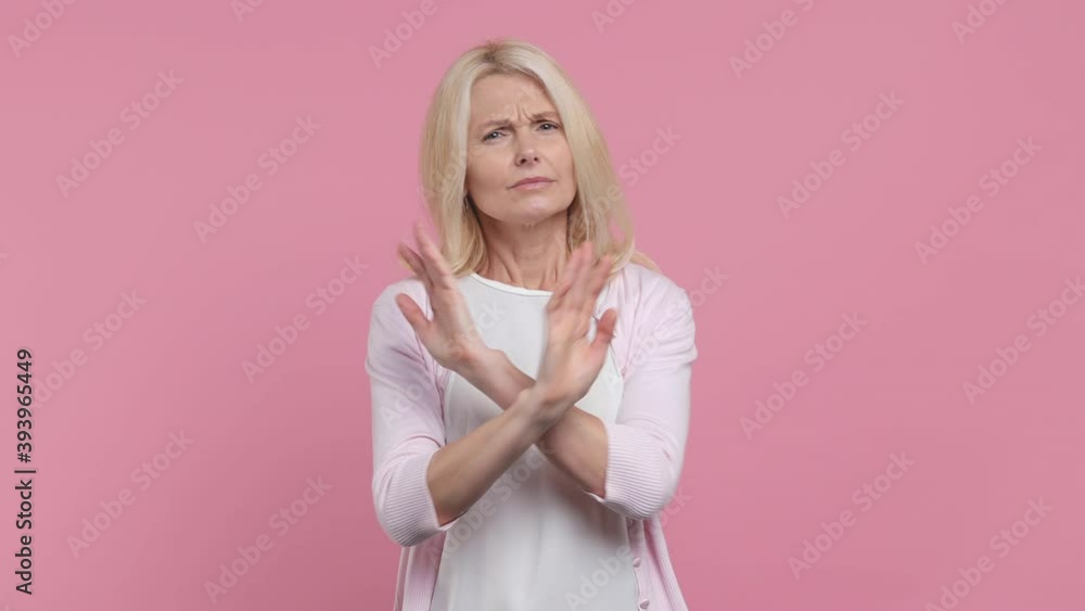Beautiful elderly gray-haired woman lady 40s 50s years old in white t-shirt pointing fingers herself ask say who me no thanks i do not need it isolated on pastel pink color background studio portrait Beautiful elderly gray-haired woman lady 40s 50s years old in white t-shirt pointing fingers herself ask say who me no thanks i do not need it isolated on pastel pink color background studio portrait