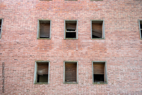 Fachada de un edificio abandonado en ruinas con persianas y ventanas rotas