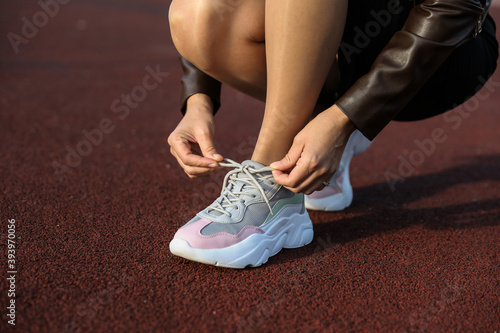 woman tying laces on sneakers on the street