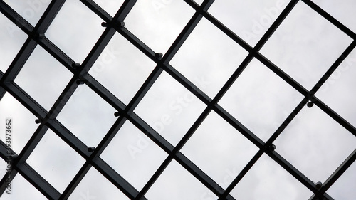 Black grid background from metal. Fence on a blue sky with cloud