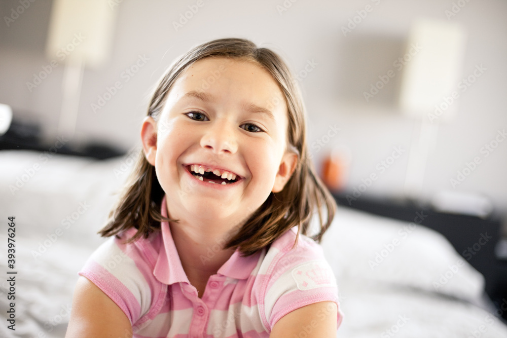 Happy Girl Laughing on Bed at Home, Missing Front Teeth, Childhood Lifestyle Portrait Happy Girl Laughing on Bed at Home, Missing Front Teeth, Childhood Lifestyle Portrait
