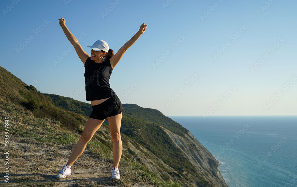 a woman enjoys conquering the top in the mountains on the coast of the sea a woman enjoys conquering the top in the mountains on the coast of the sea