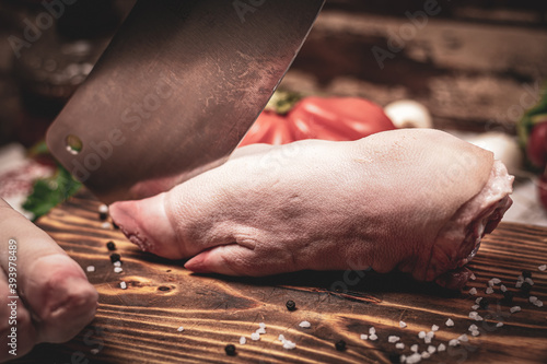 Preparing pig trotters to cook on wooden board with vegetables