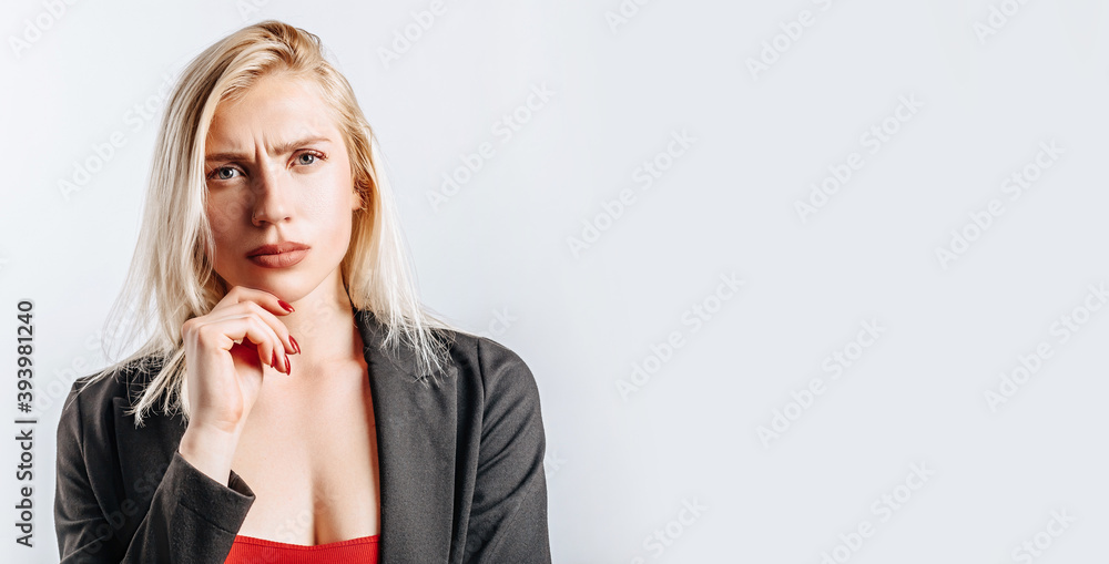 Beautiful young girl unhappy frown and thinks on gray isolated background Beautiful young girl unhappy frown and thinks on gray isolated background