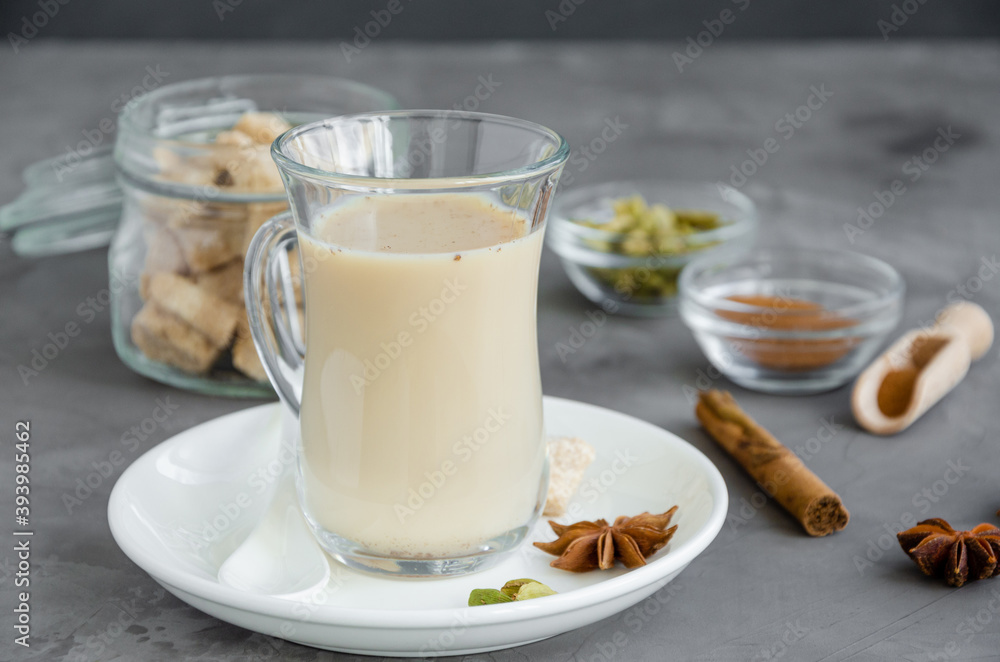 Hot tea with milk, cinnamon, cardamom, anise and other spices, Indian masala tea in a glass on a dark background. copy space. Hot tea with milk, cinnamon, cardamom, anise and other spices, Indian masala tea in a glass on a dark background. copy space.