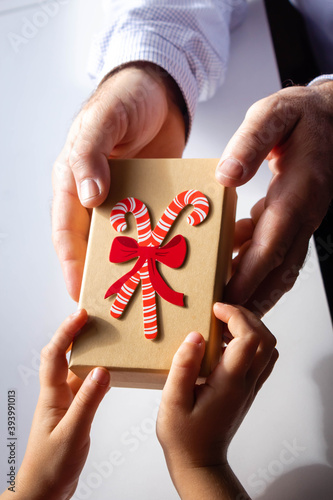 Man's hands give a gift box to a child, father gives a gift to his child, Isolated on white background, close-up