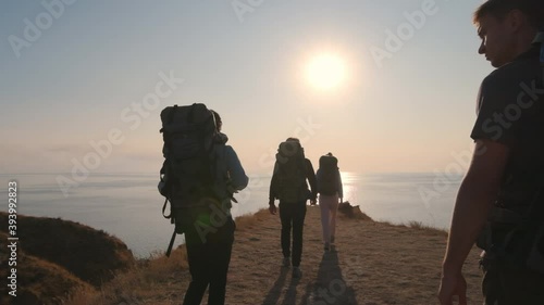 The four people with backpacks walking on mountain near the sea. slow motion