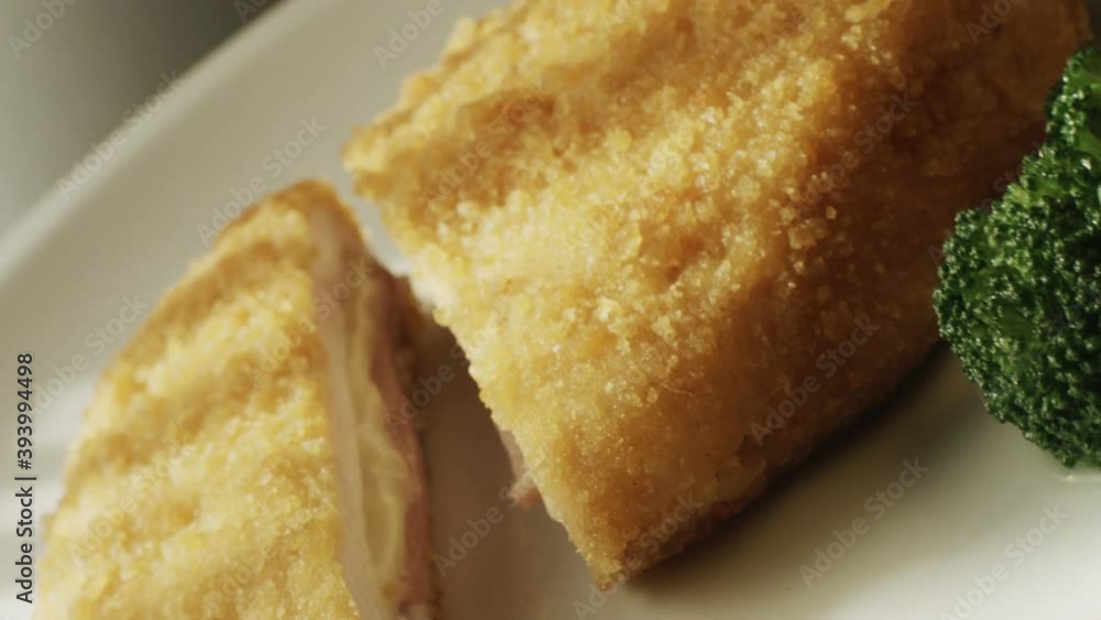 Close-up of a serving of cordon bleu served on a plate with slice of broccoli and processed cheese. Concept of high-calorie store and European cuisine Close-up of a serving of cordon bleu served on a plate with slice of broccoli and processed cheese. Concept of high-calorie store and European cuisine