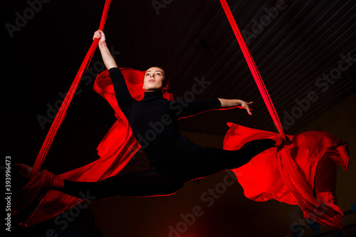 Girl aerialist doing twine on aerial canvases. Acrobatics in the air photo