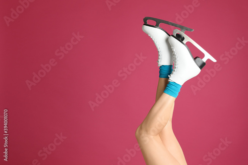 Woman in elegant white ice skates on pink background, closeup of legs. Space for text
