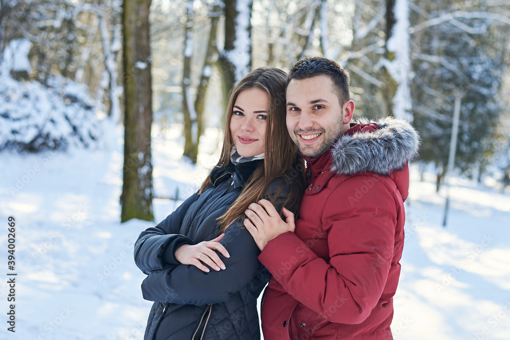 Young couple in love, enjoying winter weather outside in park forest. Brunette man in red jacket hugging woman in black. Christmas and new year holidays joy. Romantic date, relationship. Young couple in love, enjoying winter weather outside in park forest. Brunette man in red jacket hugging woman in black. Christmas and new year holidays joy. Romantic date, relationship.