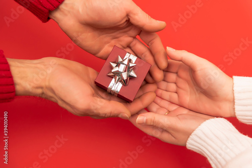 a man giving a small gift to a woman on a red background