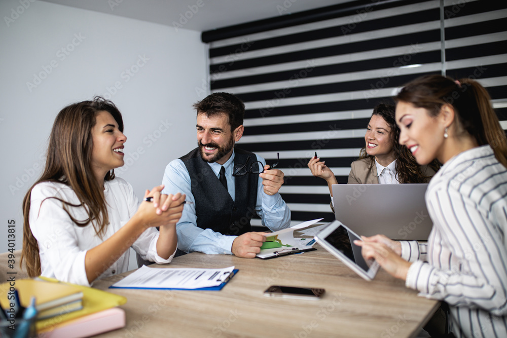 Group of four business people working together in their office on important project. They are talking and analyzing their business plan together. Group of four business people working together in their office on important project. They are talking and analyzing their business plan together.