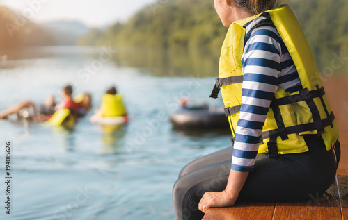 Asian woman wear life jacket sit near river, selective focus, with copy space.