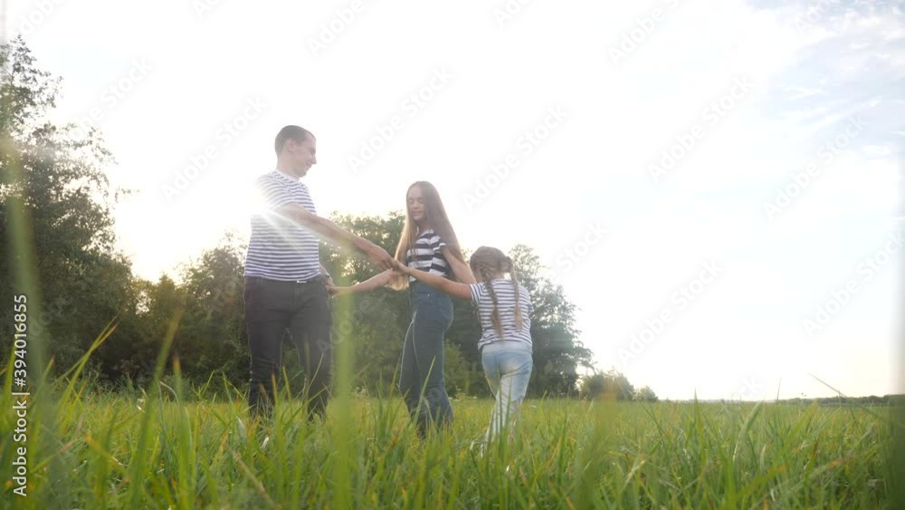 happy family mom dad and daughter play round dance. people in park kid dream concept. happy family parents with little lifestyle kid child daughter play in the park on the grass holding hands happy family mom dad and daughter play round dance. people in park kid dream concept. happy family parents with little lifestyle kid child daughter play in the park on the grass holding hands