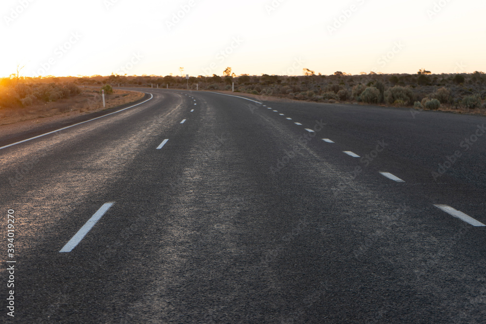 Low angle photo of an empty highway at sunset from the driver's perspective