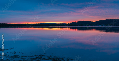 Reflection of Sunrise with soft high cloud over the waterfront