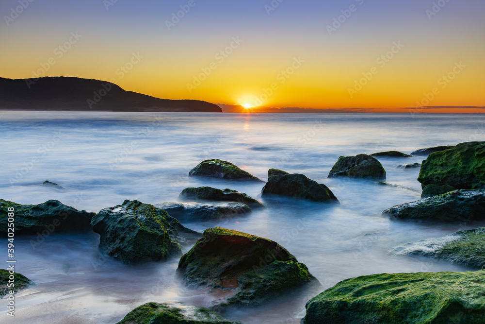 Obraz premium Sunrise by the Sea and Rocks on the Shoreline