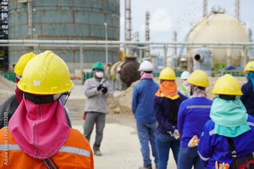 (Focus on the safety helmet) Construction worker in a safety meeting on morning talk before work at oil & Gas factory or Chemical plant under construction site.