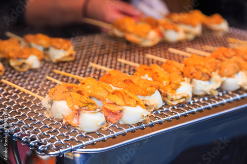scallop and sea urchin eggs grilled with smoke, japanese street food at Tsukiji Fish Market, Japan. selective focus