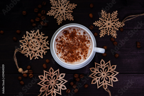 Cup of coffee and wooden snowflakes on dark wooden table, top view. Creative flat lay winter arrangement.