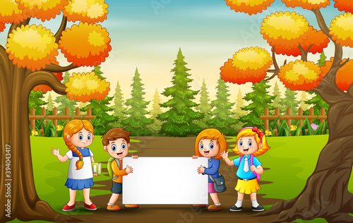 Autumn park landscape with school kids holding blank sign