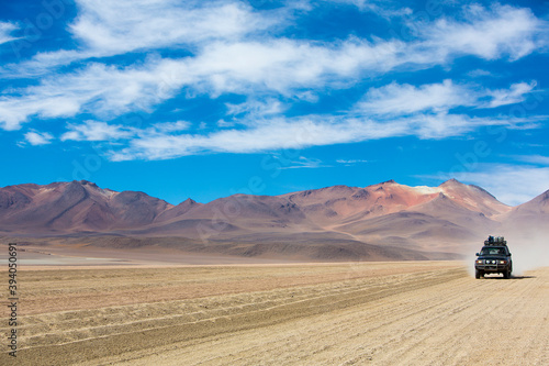 Off-road vehicle driving in the Atacama desert, Bolivia with majestic colored mountains and blue sky in Eduardo Avaroa Andean Fauna National Reserve, Bolivia 2014