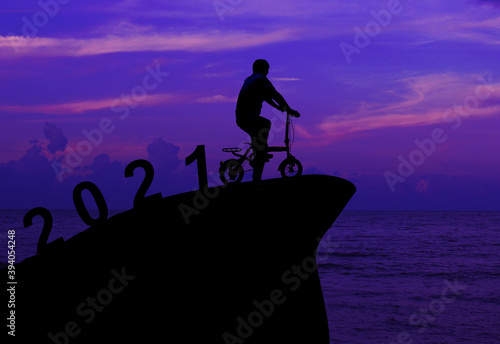 Silhouette man spin bike.Concept New Year s Eve 2020 Welcome the new year 2021 in the evening atmosphere Sunset. 