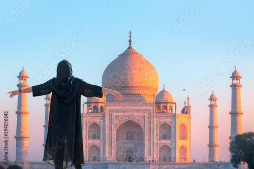 Young girl in traditional black dress raised her arms, Spectacular Taj Mahal in the background - Agra , Uttar Pradesh, India