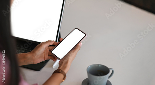 Cropped shot of young woman is sitting in front of computer tablet while using mobile phone. For graphic display montage.