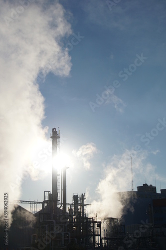 Industrial landscape with shadows of metal scaffolding and chimneys spewing environmentally harmful smoke