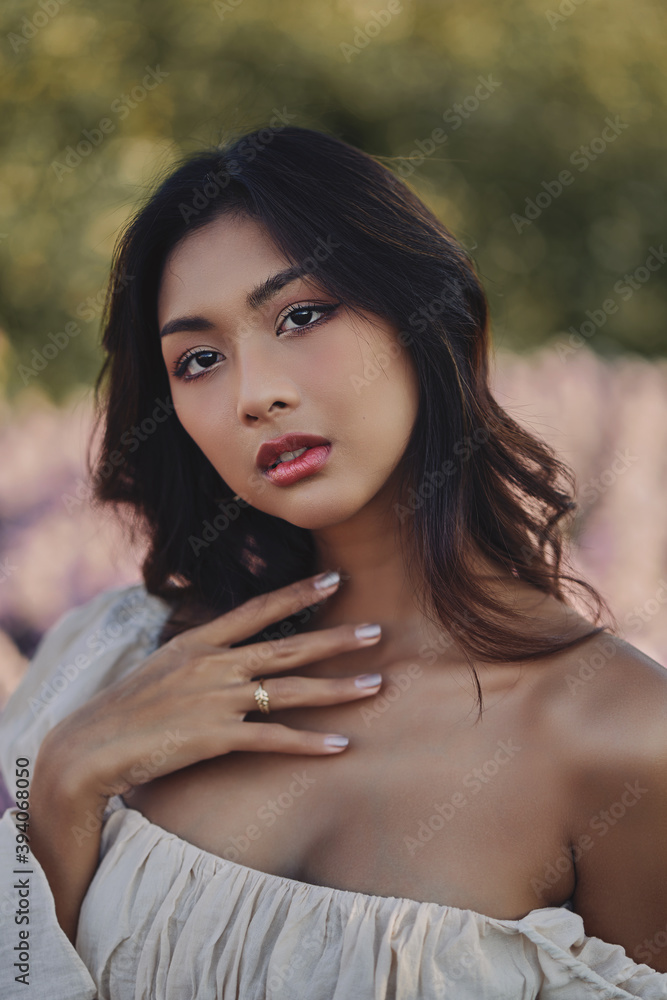 Lifestyle fashion portrait of stylish young asian woman wearing beige outfit posing at the flowers field