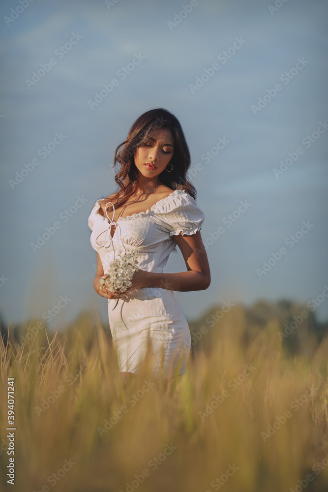 Lifestyle fashion portrait of stylish young asian woman wearing beige outfit posing at the rice field
