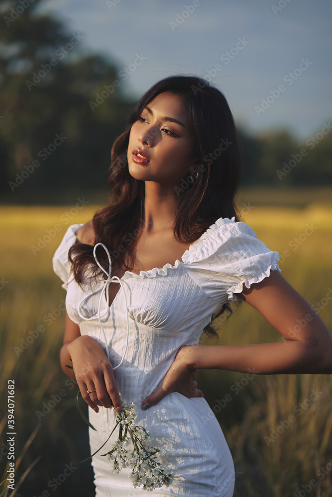Lifestyle fashion portrait of stylish young asian woman wearing beige outfit posing at the rice field