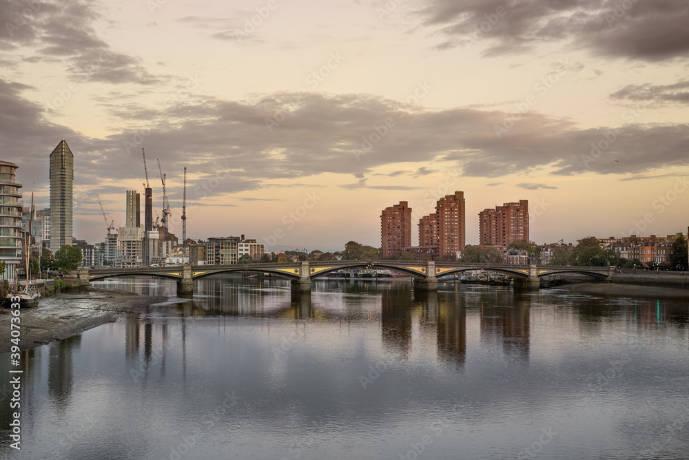 Calm sunrise over the buildings reflecting in the water in Battersea