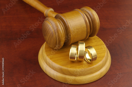 Bigamy concept, two wives wedding ring and one husband ring with judge gavel.
