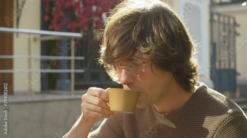 Close up portrait of hipster drinking hot coffee outdoors. Summer, sunny day